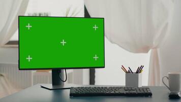 Powerful computer with chroma key green screen mock up stands on desk in living room. Pc with isolated display in home office with nobody in is ready for online business meeting video