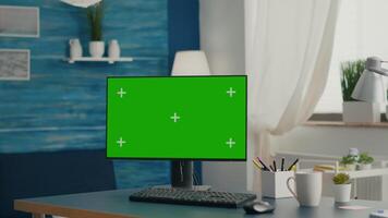 Desktop computer with mock-up green screen chroma key placed on desk in empty living room. Pc with isolated display in home office with nobody in ready for online business meeting video