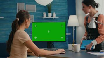 Busniess woman talking with young collegue about internet network showing on computer with mock up green screen chroma key. Caucasian female using isolated desktop pc in home office video