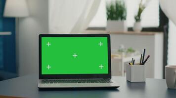 Laptop computer with mock up green screen chroma key standing on home office desk with nobody in it. Professional set up is ready for e commmerce courses using isolated pc video