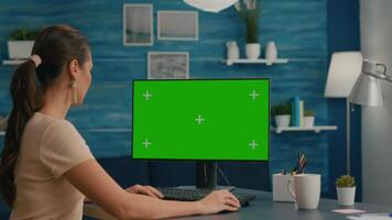 Freelancer searching the internet on green screen chroma key display using web advertisiment in chromakey PC. Home office computer with mockup video