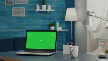 Laptop computer with mock up green screen chroma key display standing on table in living room. PC with isolated display in home office studio with nobody in it video