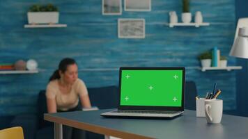 Woman sitting on desk table working on business commerce using isolated laptop computer with mock up green screen chroma key. Caucasian female typing on pc in home office studio video