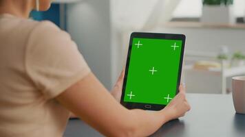 Freelancer woman holding tablet computer with mock up green screen chroma key display sitting on office room. Caucasian female browsing on internet for online project using isolated device video
