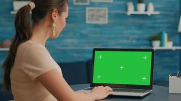 Business woman looking at laptop display with mock up green screen chroma key while working at network communication. Freelancer sitting on desk in office studio using powerful isolated pc video