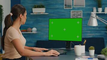Caucasian woman working on powerful computer with mock up green screen chroma key sitting on desk. Freelancer searching information for business project using isolated pc video
