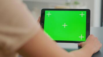 Tablet computer with mock up green screen chroma key display standing on table desk. Freelancer woman browsing on isolated device for online web communication in home office room video