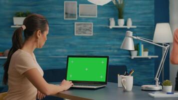 Freelancer using computer with mock up green screen chroma key for business company standing on desk table. Woman using isolated home office pc working at commerce project in home office video