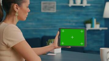 Back view of woman holding tablet computer with mock up green screen chroma key display. Caucasian female using touchscreen device for online browsing sitting in home office studio video