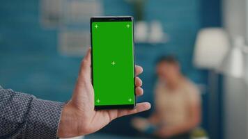 Pov of business man hands holding professional smartphone in portrait vertical mode with mock up green screen chroma key display. Freelancer using isolated phone for browsing social networks video