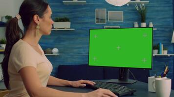 Caucasian female searching information about social media technology on computer with mock up green screen chroma key display. Woman browsing on network with isolated pc video