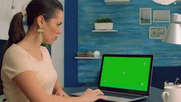 Business woman working at marketing project from home office using laptop computer with mock up green screen chroma key display. Freelancer typing isolated pc sitting at desk table video