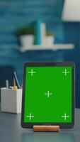 Vertical . Woman drinking a cup of coffee while looking at tablet computer with mock up green screen chroma key sitting on office table. Freelancer using with isolated gadget for internet communication project video