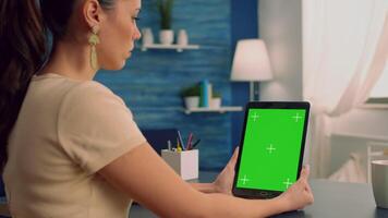 Business woman having online videocall with treamates uses tablet computer with mock up green screen chroma key display. Freelancer using isolated device for advertising project standing at office video