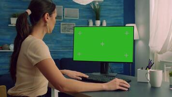Woman working at business connection with teammates on computer with mock up green screen chroma key display sitting at desk table. Freelancer browsing on network with isolated pc video