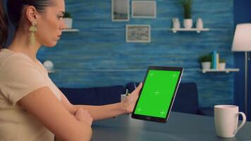 Caucasian woman looking at tablet computer with mock up green screen during online videocall . Freelancer looking at template chroma key isolated device using technology internet. video