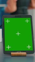 Vertical . Close up of tablet computer with mock up green screen chroma key display it is used for office work. Freelancer woman working on communication project using isolayed gadget sitting on desk video