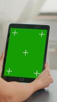 Vertical . Freelancer woman holding tablet computer with mock up green screen chroma key display sitting on office room. Caucasian female browsing on internet for online project using isolated device video