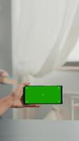 Vertical . Business woman holding phone with mock up green screen chroma key for copy space sitting on office desk. Social media influencer browsing on internet using isolated gadget video