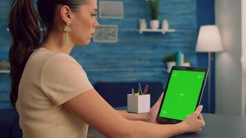 Freelancer holding tablet computer with mock up green screen chroma key display during virtual meeting. Caucasian female working on business advertising using isolated gadget, sitting at office desk video