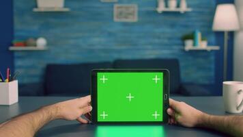 Point of view of business man hands holding tablet computer with mock up green screen chroma key display standing on desk table. Caucasian male using isolated device for digital advertising video