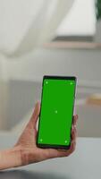 Vertical . Caucasian female having online videocall using mock up green screen chroma key phone. Business woman working at online app using isolated device siiting on office desk in home office video