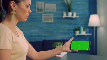 caucasico femmina Tenere isolato smartphone con finto su verde schermo croma chiave Schermo, navigazione in linea informazione su Internet mentre sua collega lettura un' libro nel sfondo video