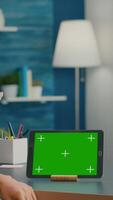Vertical . Caucasian female looking at tablet computer with mock up green screen chroma key sitting on office desk in living room. Freelancer woman browsing on social network using isolated device video