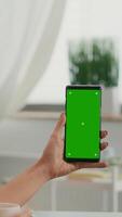 Vertical . Over shoulder of business woman using isolated smartphone with mock up green screen chroma key sitting on table desk, while talking with her friends during online videocall sitting on office desk video