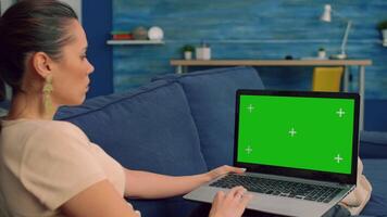 Freelancer using laptop computer with mock up green screen chroma key for online business standing sofa. Woman using isolated home office pc working at company project in living room video