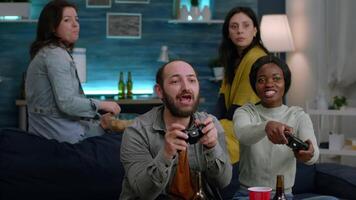 Woman with blak skin playing online videogames with man friends for gaming competition using controller. Group of mixed race winning game while sitting on sofa in living room late at night video