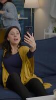 Vertical . Multiracial friends speaking with collegue man during call conference using modern smartphone. Group of multi-ethnic people hanging out together, drinking beer, having fun during night party video
