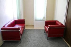 The red sofa is opposite in the room near the window photo