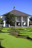 mini golf course with green grass and modern mosque during the day photo