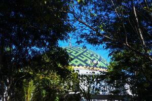 view of the mosque's dome among shady trees, against a blue sky photo