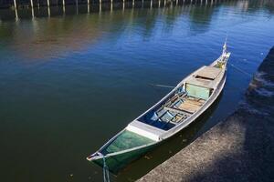 view of the river and a wooden boat on the bank of the river, against a blue sky photo