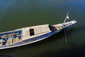 view of the river and a wooden boat on the bank of the river, against a blue sky photo