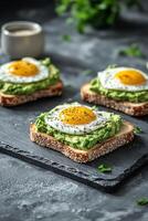 Delicious avocado toast topped with fried eggs on a slate plate in a cozy cafe setting photo