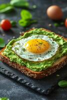 Delicious avocado toast topped with fried eggs on a slate plate in a cozy cafe setting photo