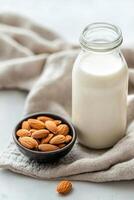 Fresh almond milk and scattered almonds in a bowl with soft linen background photo