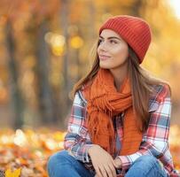 mujer en rojo sombrero disfrutando otoño en un vistoso parque foto