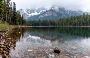 Majestic Mountains Reflected in Calm Lake Surrounded by Evergreen Forest photo