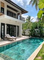 Tropical Villa With Swimming Pool Surrounded by Lush Greenery in the Afternoon Sun photo