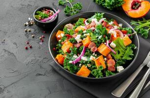 Colorful Kale Salad With Butternut Squash, Bacon, and Pine Nuts on Gray Table photo