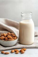 Fresh almond milk and scattered almonds in a bowl with soft linen background photo