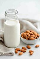 Fresh almond milk and scattered almonds in a bowl with soft linen background photo