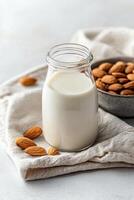 Fresh almond milk and scattered almonds in a bowl with soft linen background photo