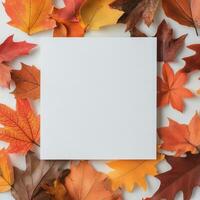 Blank square paper surrounded by vibrant autumn leaves in a warm seasonal arrangement photo