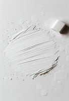 White paint smeared on a clean surface with a cap beside it photo