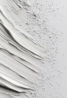 White paint smeared on a clean surface with a cap beside it photo